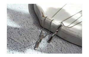 Close-up of dual geometric spiral bar pendants with polished silver finish on a bead chain