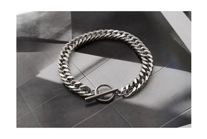 Detail of silver stainless steel Cuban chain bracelet with a toggle clasp on a magazine
