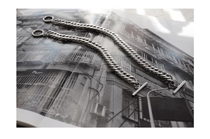 Close-up of silver Cuban link chain with OT clasp over a minimalist lifestyle background