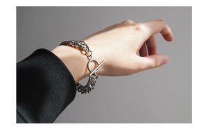 Silver Cuban link bracelet with toggle clasp shown on wrist with black long sleeve