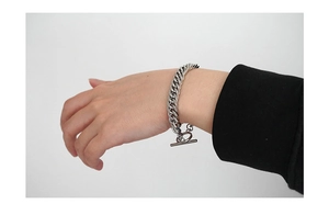 Close-up of a silver chunky Cuban chain bracelet with a polished metal toggle clasp