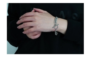 Macro detail of silver stainless steel Cuban chain bracelet with a toggle clasp on wrist