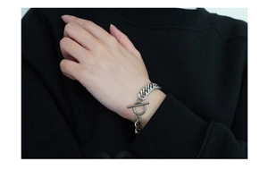 Close-up of silver stainless steel curb chain bracelet with toggle clasp on a wrist