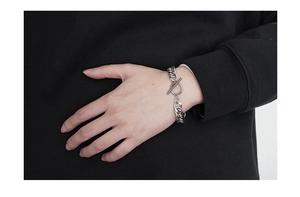 Detailed close-up of a silver Cuban chain bracelet with a T-bar OT toggle clasp closure