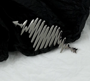 Detailed macro view of silver heartbeat pulse brooch with polished metal finish
