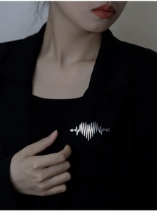 Close-up of silver heartbeat brooch pinned on a black suit jacket lapel
