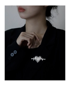 Detail of silver heart-shaped ECG brooch pinned on a black suit lapel for high contrast