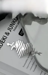 Macro shot of silver heartbeat EKG brooch with sleek metallic finish on book background