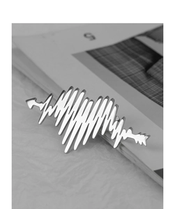 Macro shot of silver heartbeat pulse brooch with arrow on a minimalist background