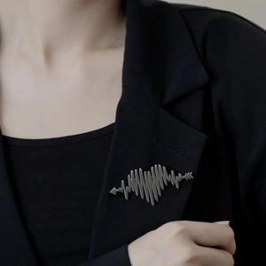 Silver heartbeat EKG brooch with arrow design worn on a professional black suit lapel