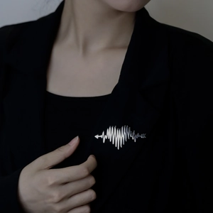 Silver heartbeat pulse brooch with arrow design on a black suit lapel for women