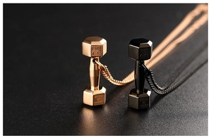 Macro shot of rose gold and black dumbbell pendants with Phil 4:13 Bible engraving