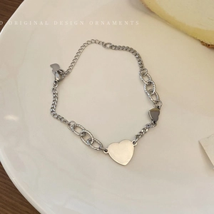 Detailed close-up of textured chain links and polished heart charms on a silver bracelet