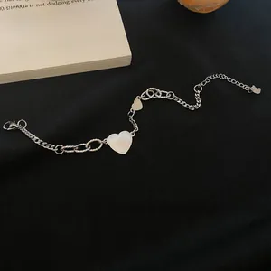 Detail of titanium heart chain bracelet with mixed link textures on black fabric
