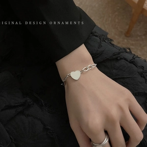 Close-up of mixed chain bracelet with heart pendant on wrist for a minimalist retro style