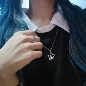 Gros plan du collier pendentif étoile astronaute et de la bague vintage portés par un mannequin