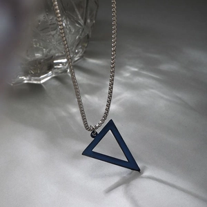 Détail d'un pendentif triangle bleu foncé minimaliste sur une chaîne à billes argentée