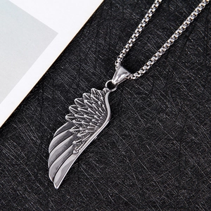 Gros plan sur un pendentif aile d'ange rétro en argent avec plumes gravées et oxydation
