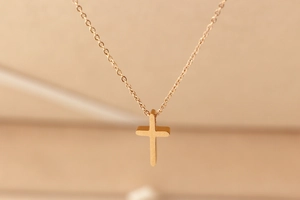 Macro shot of an elegant minimalist rose gold cross pendant on a fine chain necklace