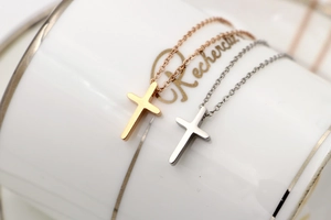 Close-up of minimalist gold and silver cross necklaces resting on a white porcelain cup