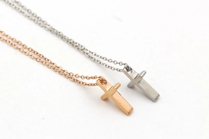 Macro view of mini cross necklaces in rose gold and silver finishes with O-chains