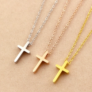 Close-up of minimalist mini cross pendant necklaces in gold, silver, and rose gold finish
