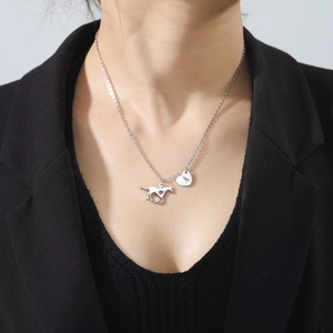Detail view of silver stainless steel horse pendant and heart tag with letter A on a chain