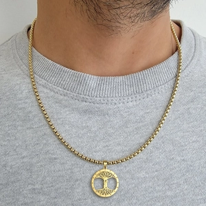 Detailansicht der goldenen Lebensbaum-Halskette auf einem grauen Pullover