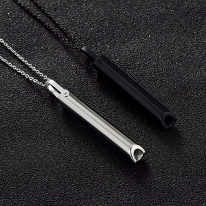 Detalle de colgantes de silbato para meditación en acero inoxidable negro y plateado