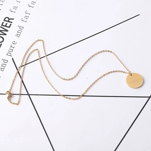 Detail of minimalist gold round disk pendant with lobster clasp on stainless steel chain