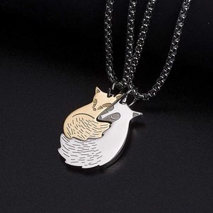 Détail macro de deux pendentifs renard imbriqués en or et argent avec chaînes