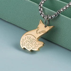 Vue macro d'un pendentif renard doré avec chaîne carrée argentée sur fond bleu clair