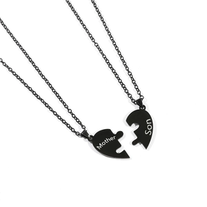Detail of black stainless steel mother and son puzzle heart necklaces with engraved text