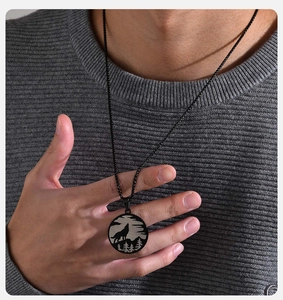 Detail view of male model wearing black stainless steel wolf forest pendant necklace