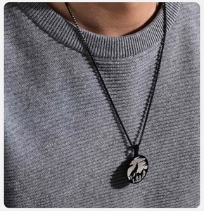 Detail of a men's stainless steel necklace featuring a forest wolf moon pendant on a gray sweater