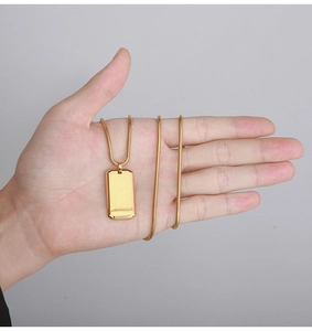 Close-up of a polished gold rectangular military dog tag pendant on a snake chain