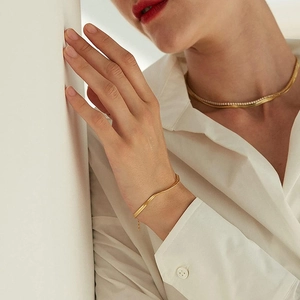 Minimalist gold snake chain set with necklace and bracelet worn on white shirt