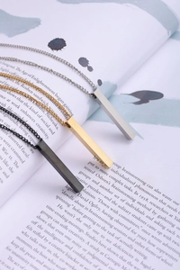 Pendentifs géométriques minimalistes en or, argent et noir posés sur un magazine