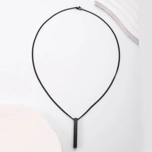 Gros plan sur pendentif rectangulaire noir mat minimaliste avec une chaîne fine