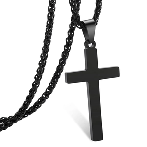 Détail macro d'un pendentif croix en acier noir mat avec une chaîne maille épi robuste