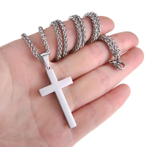 Gros plan d'une chaîne épi en argent et d'un pendentif croix poli en acier inoxydable