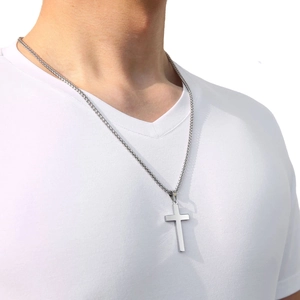 Gros plan du pendentif croix en acier inoxydable poli avec chaîne maille blé sur modèle