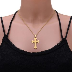 Vue macro d'un pendentif croix en acier doré avec gravure Jesus sur mannequin