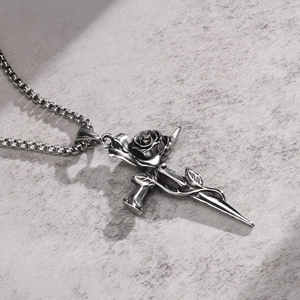 Detail of vintage thorn rose cross pendant with box chain on textured stone background