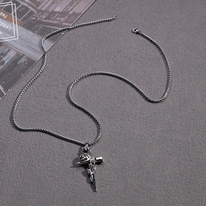 Detail of vintage gothic rose sword pendant with box chain on dark textured surface