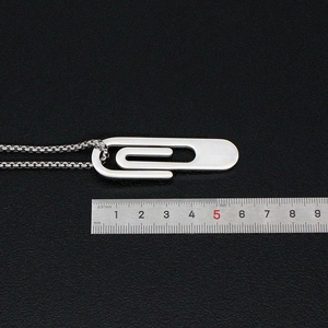 Macro shot of silver paperclip pendant with stainless steel ruler showing 35mm length