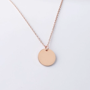 Dettaglio del ciondolo circolare in oro rosa lucido su una sottile catena minimalista