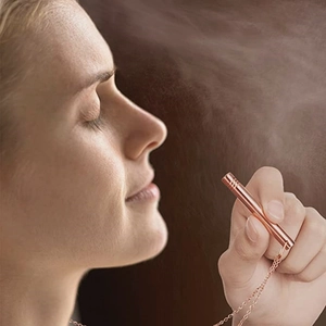 Close-up of rose gold mindfulness breathing whistle necklace worn by model in serene setting
