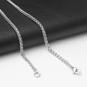 Détail de la chaîne maille épi argentée avec fermoir mousqueton sur fond en cuir noir et blanc