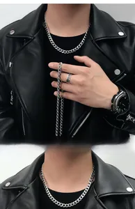 Détail d'un collier chaîne cubaine en acier argenté porté avec une veste en cuir noir